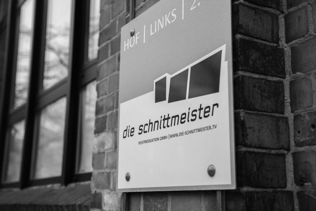Firmenschild der Schnittmeister Postproduktion GmbH an einer Backsteinwand